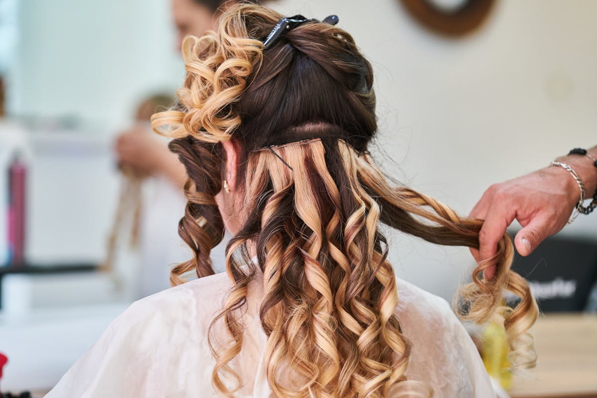 Coiffeuse en train de réaliser un balayage bouclé au Studio Cheveux Marais